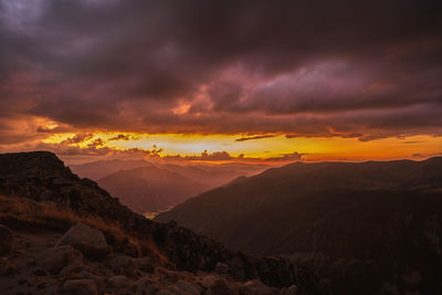 Scenic view of mountains against dramatic sky during sunset