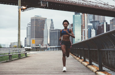 Woman exercising on bridge in city