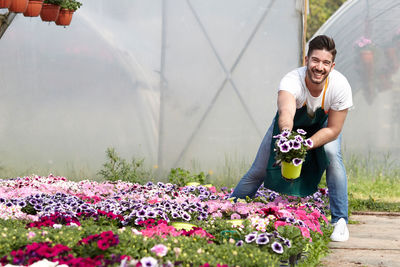 Smiling young woman standing by flowering plants