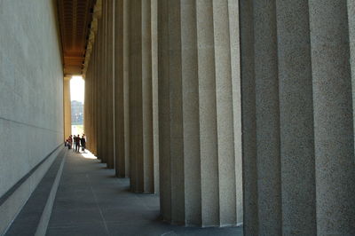 People walking in corridor along pillars and wall