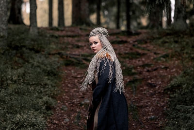 Young woman standing against trees