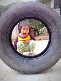 Portrait of smiling girl seen through tire outdoors