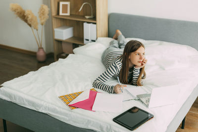 High angle view of woman using mobile phone on bed at home