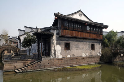 Exterior of old building by lake against sky