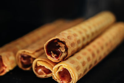 Sweet wafer rolls with chocolate condensed milk on dark background