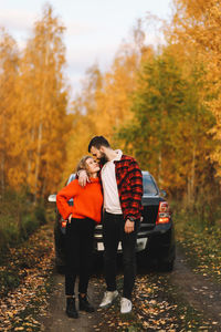 Friends standing by trees during autumn