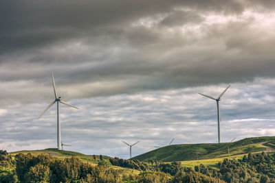 Wind turbines on field against sky