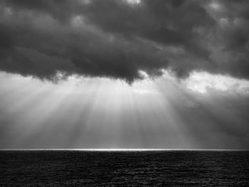 Sunlight streaming through clouds over sea