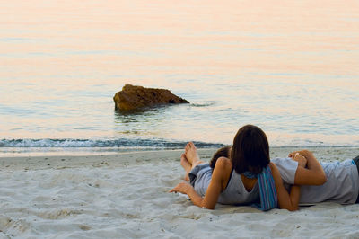 People relaxing on shore at beach against sky