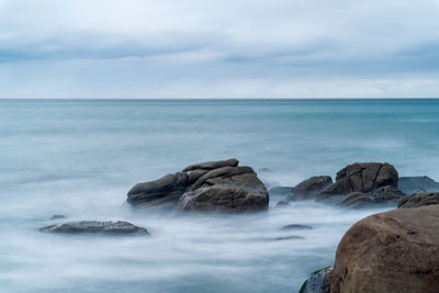 Scenic view of rocks in sea against sky