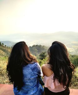 Rear view of woman looking at mountains against sky