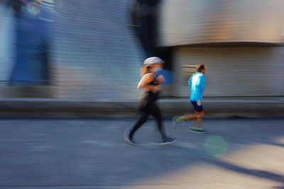 Blurred motion of people running on street in city