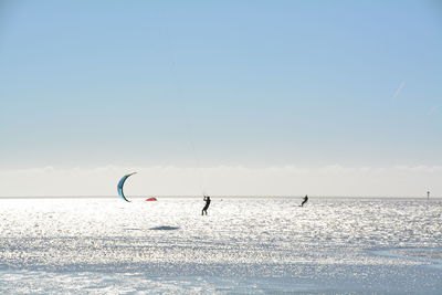 People kiteboarding at sea against sky