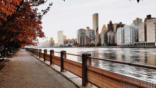 Cityscape by river against sky