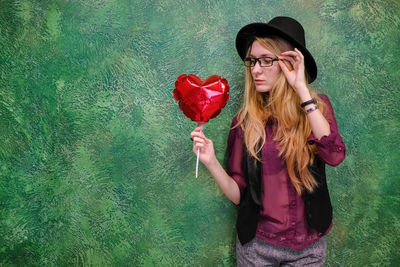 Beautiful young woman with red umbrella standing on rock