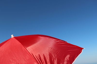 Cropped image of red umbrella against blue sky