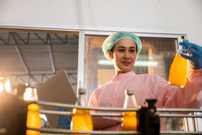 Portrait of smiling young woman using mobile phone while standing in cafe