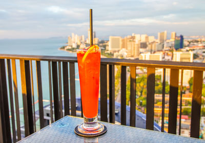 Close-up of drink on table by railing against sea