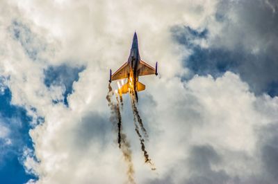 Low angle view of airplane flying against cloudy sky