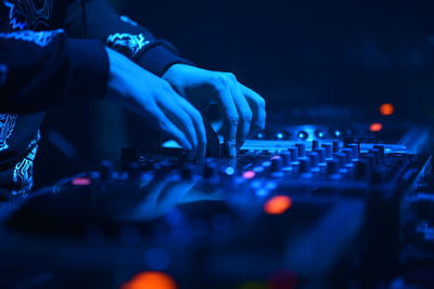Midsection of man playing sound mixer at club