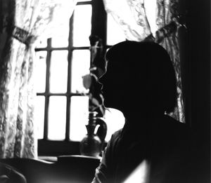 Close-up of silhouette woman against window