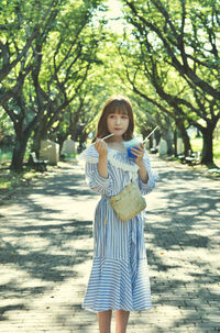 Portrait of smiling woman standing against trees