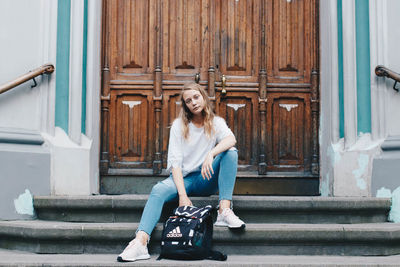 Portrait of smiling woman sitting on staircase outside building