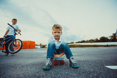 Portrait of boy sitting on motorcycle against sky