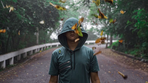 Man standing on road against trees