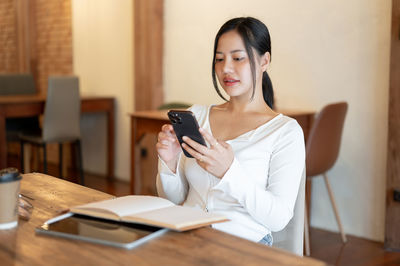 Young woman using mobile phone while sitting at home