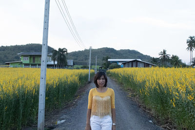 Portrait of woman standing against yellow flowering plants