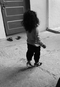 Rear view of girl on footpath against house