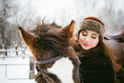 Close-up of young woman with horse in winter
