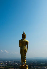 Buddha statue against blue sky in city