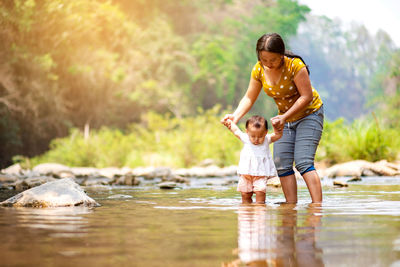 Mother holding daughter hands in river