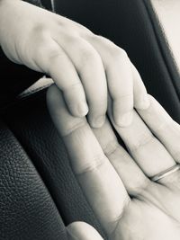 Close-up of baby touching parent hand in car
