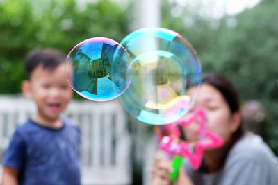 Close-up of bubbles with mother and son playing in park