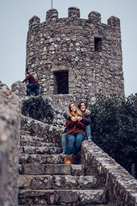 Low angle view of couple on brick wall