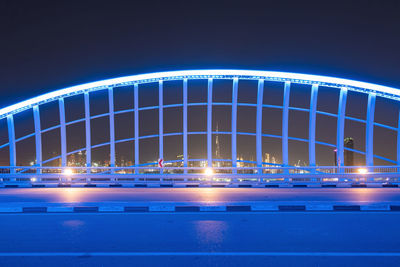 Illuminated bridge against blue sky at night