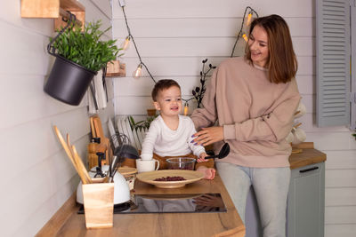 Young woman and little son play in the kitchen with dry red beans, together