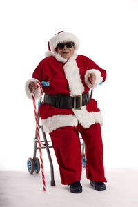 A nonagenarian in a santa claus costume sitting on a walker with a white background.