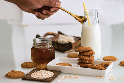 Cropped hand pouring honey on cookies