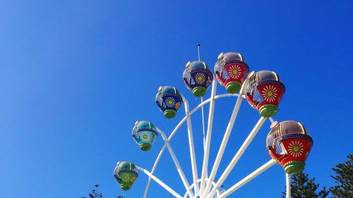 Low angle view of ferris wheel against clear blue sky