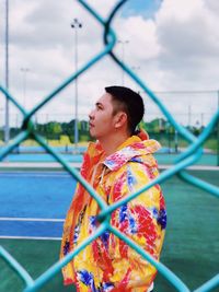 Man seen through chainlink fence against sky