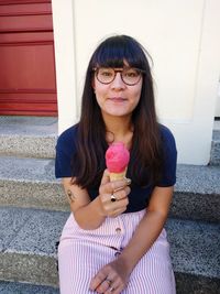 Portrait of woman holding ice cream sitting on steps