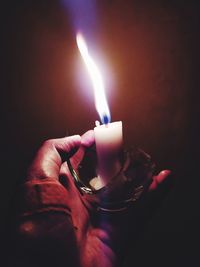 Close-up of hand holding burning candle