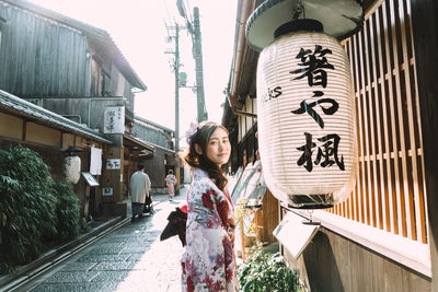 Portrait of woman standing by lantern in city