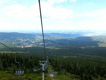 Overhead cable car over mountains against sky