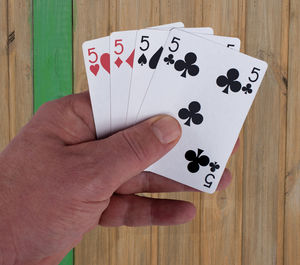 Cropped hand holding cards at wooden table