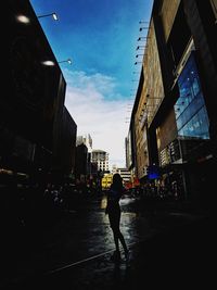 Rear view of woman walking on street amidst buildings in city